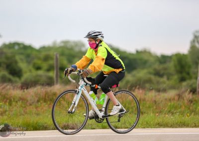 Bright neon green and black bike safety jersey with woman riding a road bike outdoors.