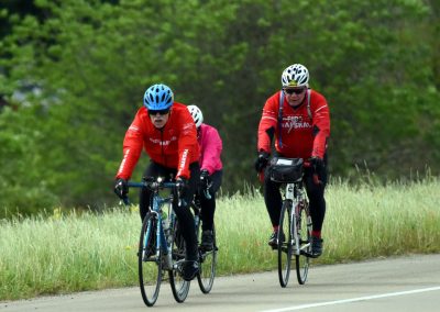 Bicycle riders wearing red jackets on Greenway trail during daytime.