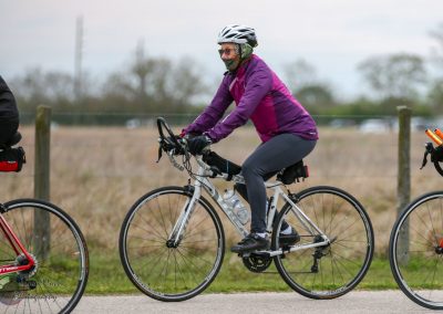 Vibrant cyclist riding on scenic trail with colorful jacket and helmet during daytime.