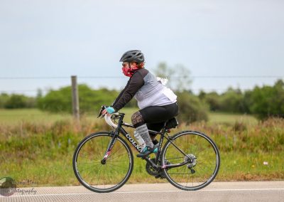 Vegan cyclist riding a road bike on a scenic route during daytime.
