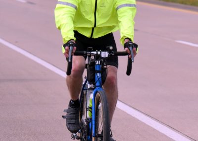 Bright yellow cycling jacket and helmet on a man riding a bike outdoors.