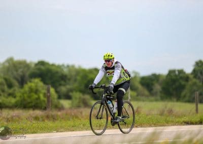 Vibrant cyclist riding a bike on a rural trail with lush greenery during daytime.