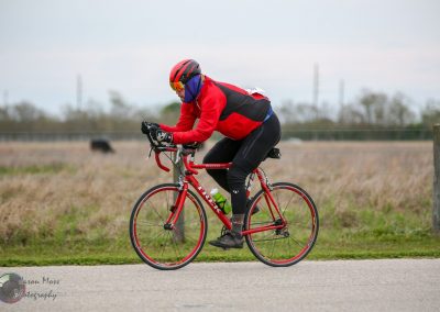 Velo cyclist riding on open road in race or training, showcasing endurance and athleticism.