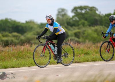 Bright female cyclist riding on scenic road during Bluebonnet Express event, promoting outdoor biking.