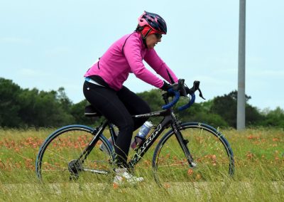 Vibrant cyclist riding a mountain bike through a grassy field with flowers, showcasing outdoor biking adventures.