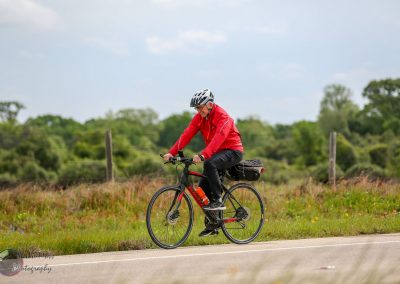 Man riding a Black and Red e-bike on a scenic outdoor path in Texas during daytime.