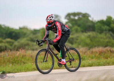 Stylish cyclist riding on scenic road with Bluebonnet Express branding, promoting Texas cycling events and bike tours.