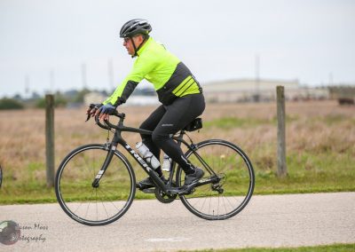 High-visibility cyclist riding on a flat bike path in Texas, promoting safe biking with Bluebonnet Express.