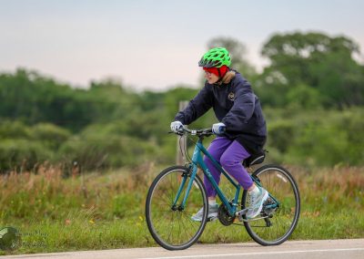 Bright woman biking outdoors in safety helmet on scenic trail - Bluebonnet Express bike ride.