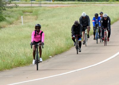 Vibrant group cycling along scenic bike trail on Bluebonnet Express route, promoting outdoor activity and healthy lifestyle.