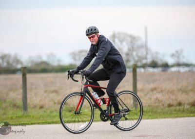 Comfortable adult cycling with Bluebonnet Express bike in outdoor park setting.