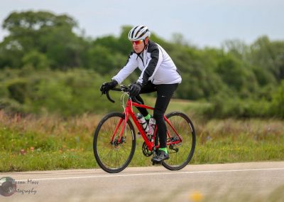Velo cyclist riding on a scenic trail during daytime in a rural setting, promoting outdoor biking adventure.