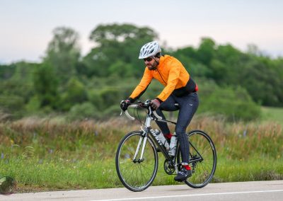 Vibrant cyclist riding on scenic outdoor trail with lush green landscape during daytime.