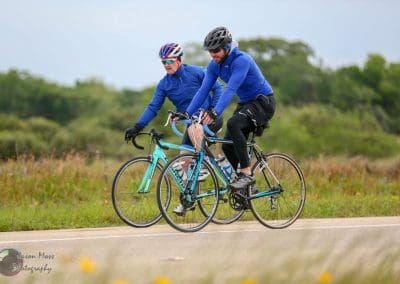 Bright blue cyclists riding together outdoors in nature, enjoying a scenic bike ride with Bluebonnet Express.