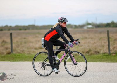 High-performance cyclist riding a Trek road bike on open road in Texas, promoting Bluebonnet Express.