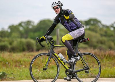 Vegan cyclist riding a black and yellow road bike on a scenic trail, promoting eco-friendly transportation.