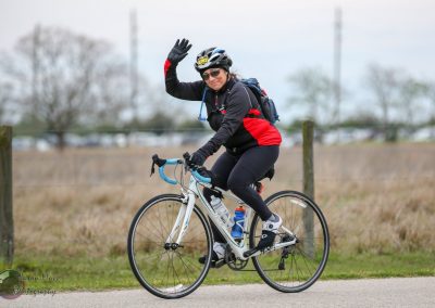 Bright female cyclist riding a road bike during outdoor ride, showcasing the Bluebonnet Express cycling route.