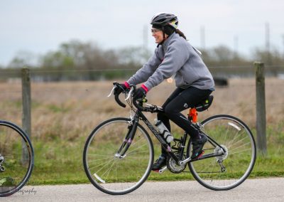 Vibrant woman cycling on a scenic outdoor trail with Bluebonnet Express branding.