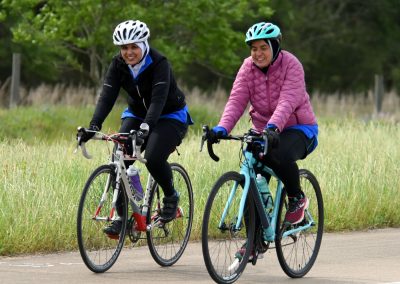 Bright women cycling on scenic trail with Bluebonnet Express bikes, enjoying outdoor adventure and nature.