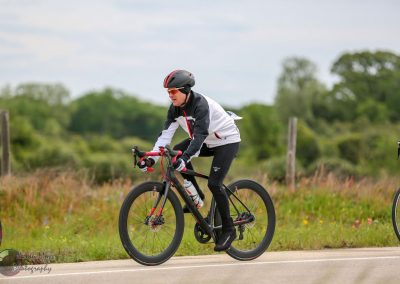 Vermont cyclist riding a Black and Red Bluebonnet Express bike on a rural road during daytime.