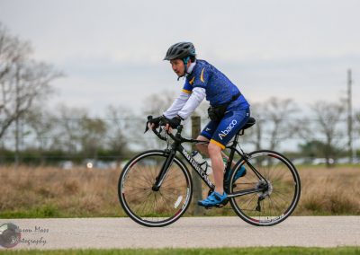 High-performance cyclist riding on the road, promoting Bluebonnet Express biking events.