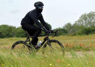 High-performance cyclist riding in a grassy field, emphasizing outdoor biking, cycling gear, and adventure.