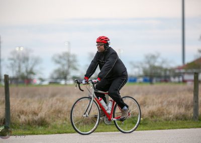 Comfortable cyclist riding a bike outdoors with safety gear in a park setting.