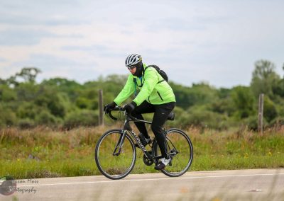 Vibrant cyclist in lime green jacket on rural bike trail, perfect for Bluebonnet Express bike tours.