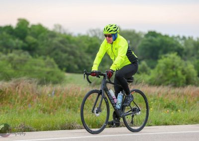 Bright yellow cycling jacket with bike helmet on a professional road cycling bike in a vibrant outdoor setting.