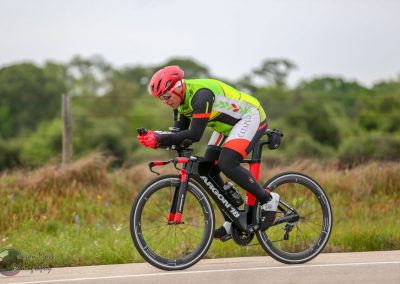 Vibrant cyclist on Bluebonnet Express electric bike enjoying outdoor ride in lush green landscape.