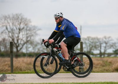 Vibrant cyclist riding a mountain bike on a scenic outdoor trail, promoting Bluebonnet Express cycling tours.