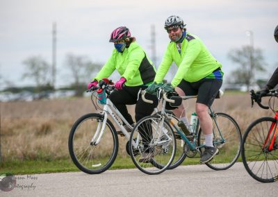 Bright green cycling jerseys on bikers on a scenic trail, promoting Bluebonnet Express bicycle services.