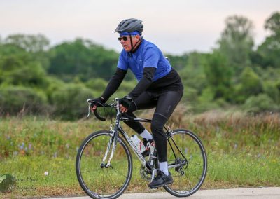 High-performance cyclist riding on a scenic trail, promoting Bluebonnet Express cycling service.