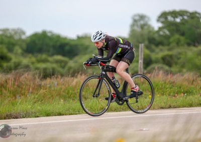 High-performance cyclist riding outdoors on a black carbon fiber bike with focused determination.