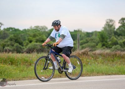 Colorful rider on Bluebonnet Express mountain bike through scenic countryside.