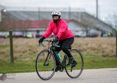 Vegan Bicycle rider with pink jacket cycling outdoors on a cloudy day.