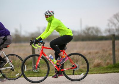 Bright neon yellow bike jersey and face covering on cyclist riding a red bike for Bluebonnet Express.