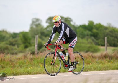 Brightly colored cyclist riding on scenic rural road for Bluebonnet Express event.