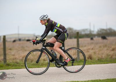 High-performance cyclist riding a sleek black road bike on a scenic outdoor trail.