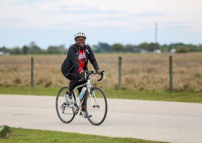 Bright woman enjoying cycling outdoors on a sunny day with Bluebonnet Express branding, promoting active transportation.