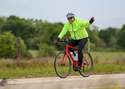 Vibrant cyclist wearing a neon green jacket on a red bike, offering directions during a ride.