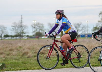 Vibrant female cyclist riding a red mountain bike on a paved trail outdoors.