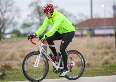 Velo cyclist in neon jacket riding on bike trail, outdoors in rural setting.