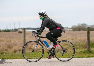 Bright female cyclist riding a bike on a rural path with a protective helmet and biking gear.