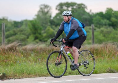 Bright man cycling outdoors with a backpack on a scenic trail, emphasizing active transportation and fitness.