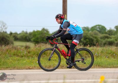 Velo cyclist riding on scenic outdoor trail with Bluebonnet Express branding.