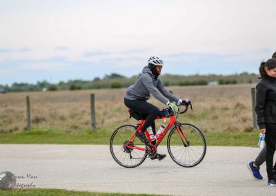 Bright red Bluebonnet Express road bike with cyclist riding outdoors on a paved trail in nature.