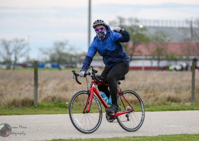 Bright cyclist riding a red bike outdoors during daytime, emphasizing eco-friendly transportation.