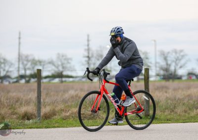 Rider on red bike with helmet enjoying outdoor cycling in open field.