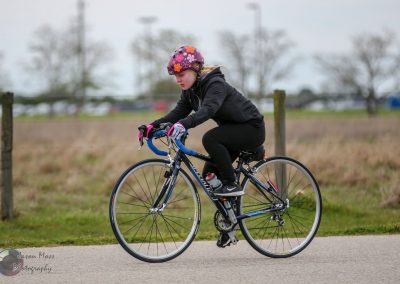 Brightly colored girl cycling on bike path with bluebonnet express branding in background.